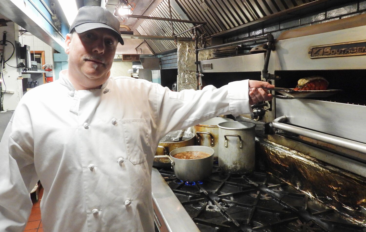 Head Chef Paul Prior pulls a lobster tail out, ready to serve at Captain John's in Sylvan Beach.