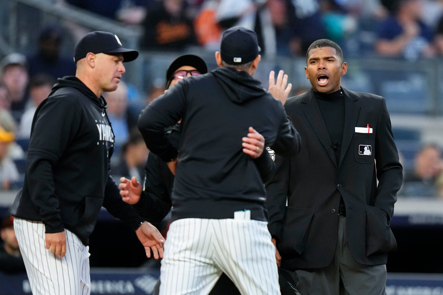 Home plate umpire Edwin Moscoso, right, talks to New York Yankees manager Aaron Boone as Boone is restrained after being ejected during the third inning of the team’s game against the Baltimore Orioles on Thursday night in New York.