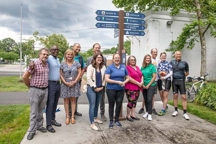 Elected officials, county representatives, cyclists and community members gathered on May 29 for the unveiling of a new sign at the intersection of Jones Station Road and the B&A Trail that memorializes a local cyclist who was killed in a crash and informs passersby about regional and national trail networks.
