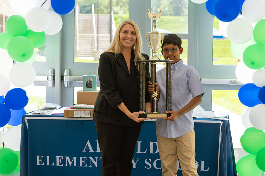 Arnold Elementary School Principal Shauna Kauffman and Johan Zacharia hoisted a trophy after the fifth-grader won a nationwide InvestWrite competition.