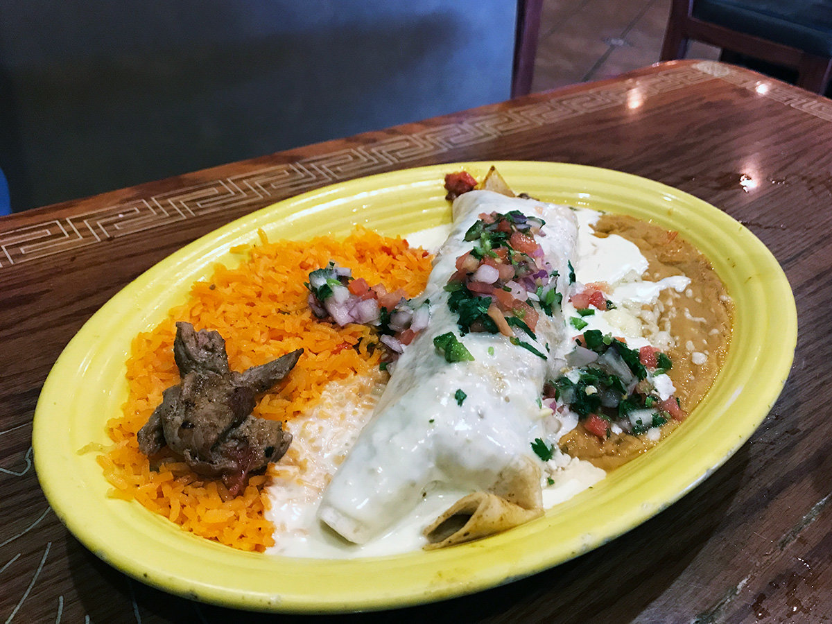 The burrito norteno is stuffed with seasoned, grilled steak or chicken and topped with spicy queso and fresh pico de gallo on a bed of Spanish rice and beans.