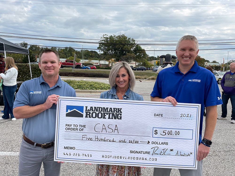 Rob Calhan (left), Landmark Roofing co-owner and president of sales, and Artie Hendricks, Landmark Roofing co-owner and president of operations, gave $500 to Anne Arundel County CASA Executive Director Rebecca Tingle during Shoptoberfest on October 23.