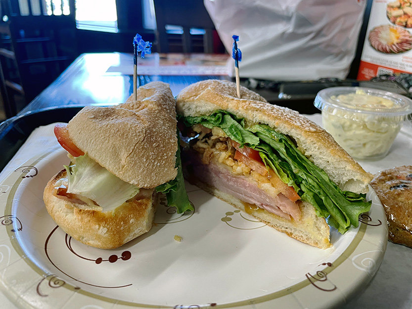 “The Honeybaked" sandwich features sliced ham on a toasted ciabatta roll with lettuce, tomatoes, crispy onions and pickles, and zesty mustard (or your choice of condiment).