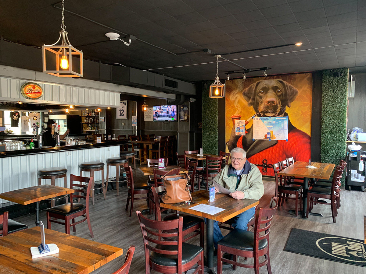 Inside, the restaurant features polished wood chairs and tables, a sleek bar, sophisticated hanging lights, and dog art.