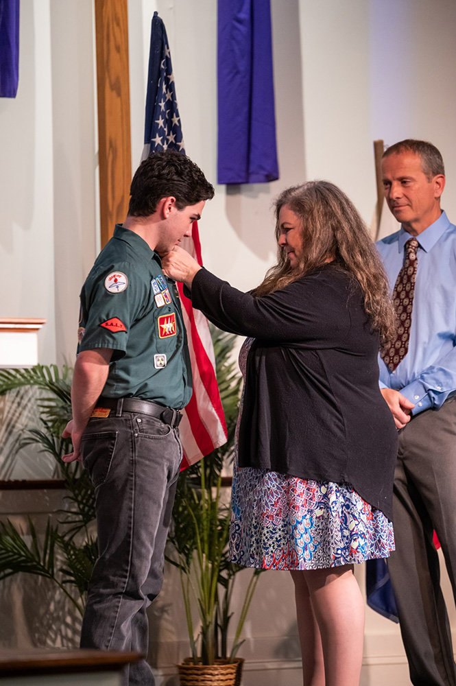 Seth Ratajczak’s mom attached the Herald of Christ pin to her son during a ceremony on April 7.