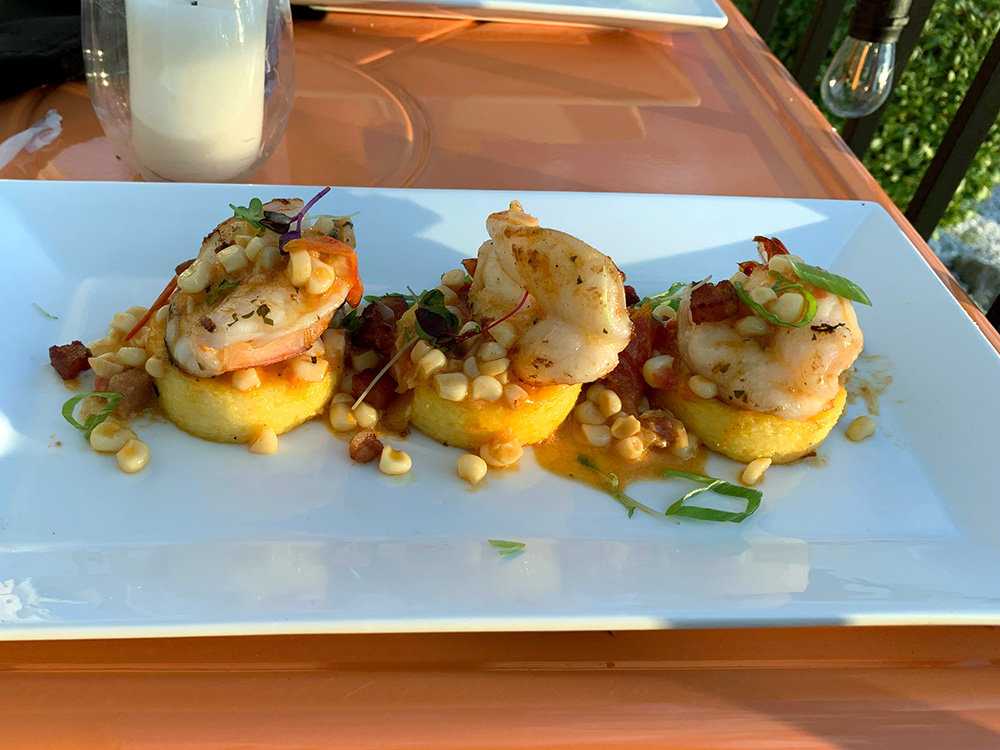 The colossal shrimp and polenta cakes are served with sweet corn and blistered tomatoes.