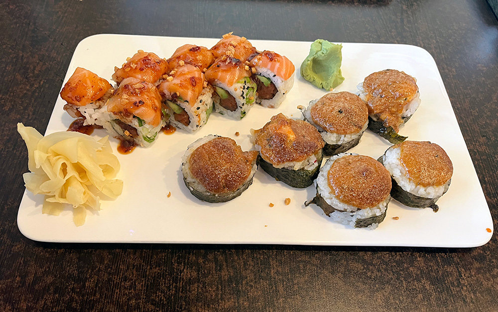 The Sarah’s roll (top) contains spicy tuna and creamy avocado wrapped in rice and seaweed. It’s topped with raw salmon, a sweet Hawaiian barbecue sauce, and chunks of fresh garlic. The dynamite roll (bottom) combines flaky salmon, cooked tuna, rice, seaweed and a spicy sauce.