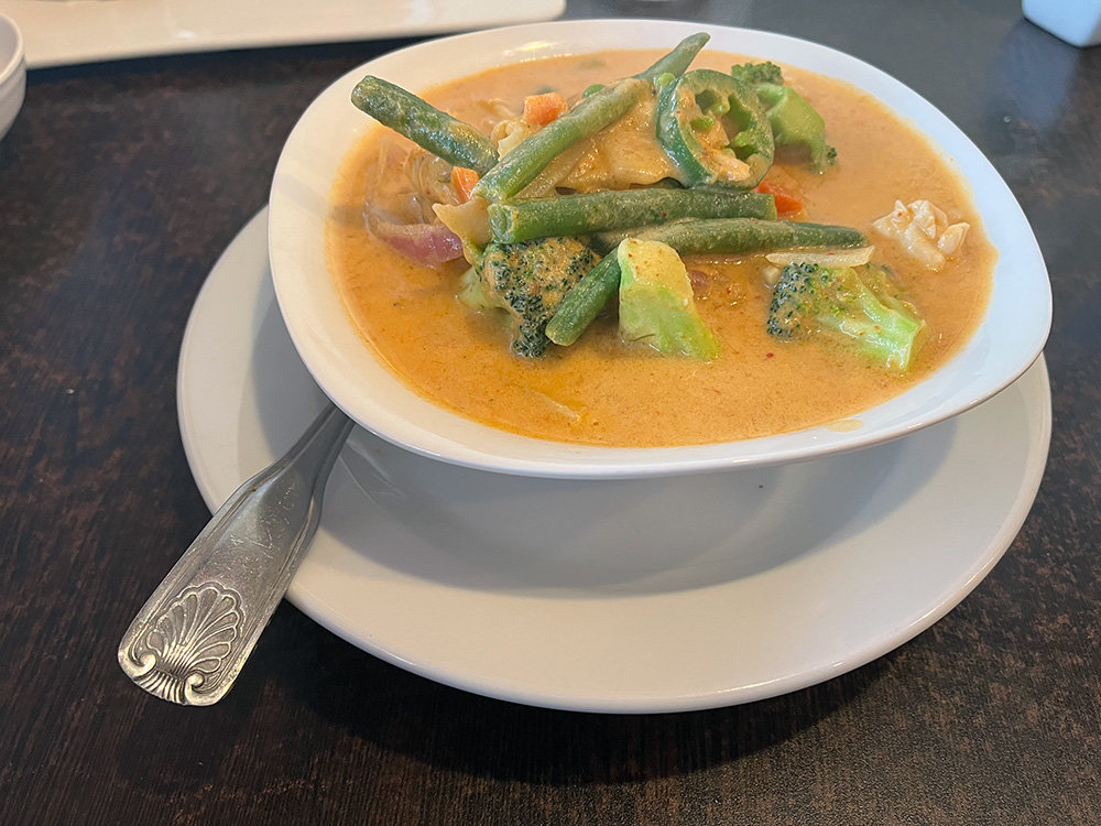 A hearty array of vegetables including broccoli, green beans, red onions, carrots, peas, bamboo shoots, spinach and jalapenos rose above the Thai curry broth.