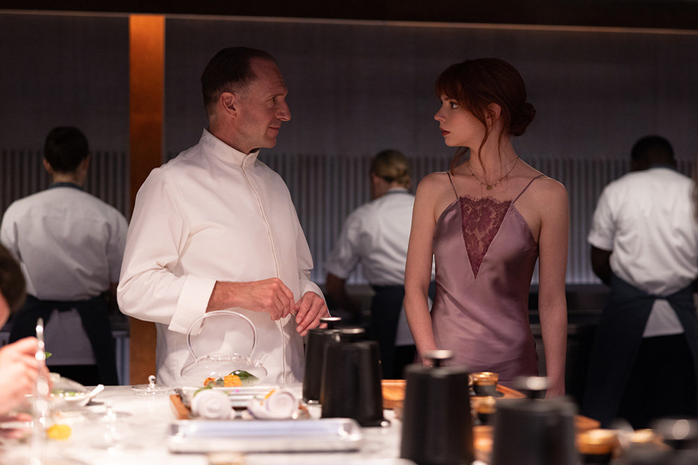 In “The Menu,” Anya Taylor-Joy (right) and her date travel to a private island to enjoy a one-of-a-kind dining experience made possible by the chef, played by Ralph Fiennes (left).