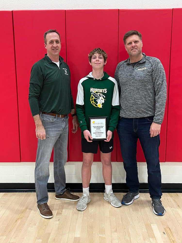 Green Hornets basketball commissioner Kurt Cerny (left) and Green Hornets 13U head coach Mark Merolla (right) presented eighth-grader Liam Kinslow with the Anne Arundel County Sportsmanship Award following the winter basketball season.