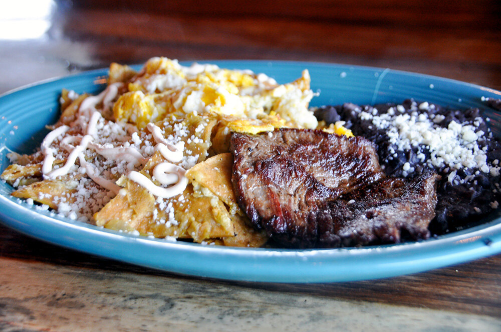 Chilaquiles are fried corn tortillas sauteed with grilled steak, onions, either salsa verde or salsa roja, and topped with queso fresco. They are served with two eggs and a side of black beans.