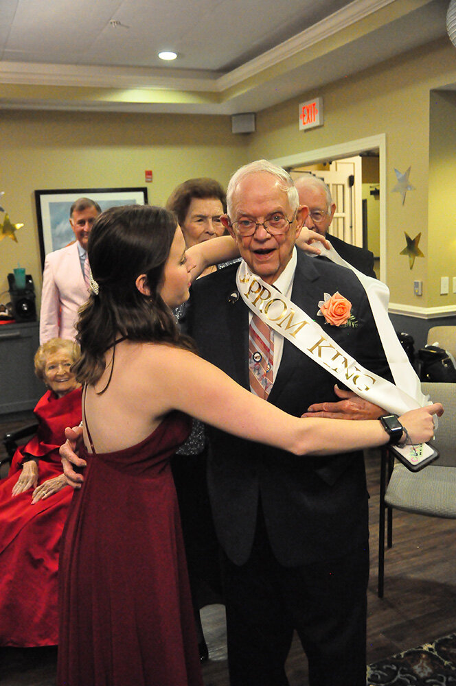 Emme Ray, Brightview Severna Park vibrant living assistant, hung a sash around one of the prom kings, Preston Seely.