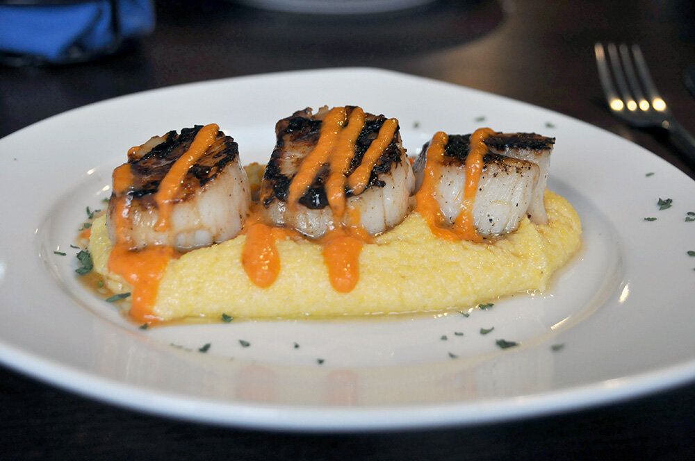 Scallops con Polenta is an appetizer at Luna Blu that features pan-seared scallops served over a creamy polenta, drizzled with a red pepper puree.