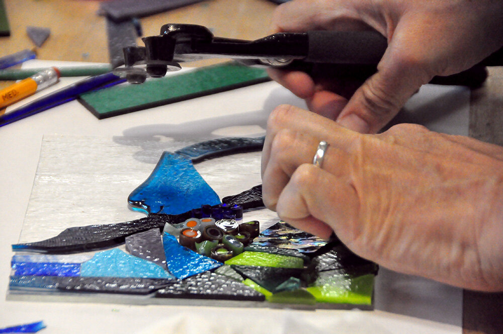 A participant in an August 17 free glass fusing workshop for veterans and servicemembers put pieces of glass down during the creation of her dish.