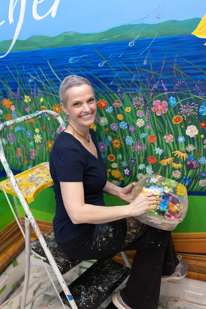 Gayle Mangan Kassal, the mural artist who oversaw Broadneck Elementary School’s legacy project, adds final touches to the hundreds of flowers students painted.