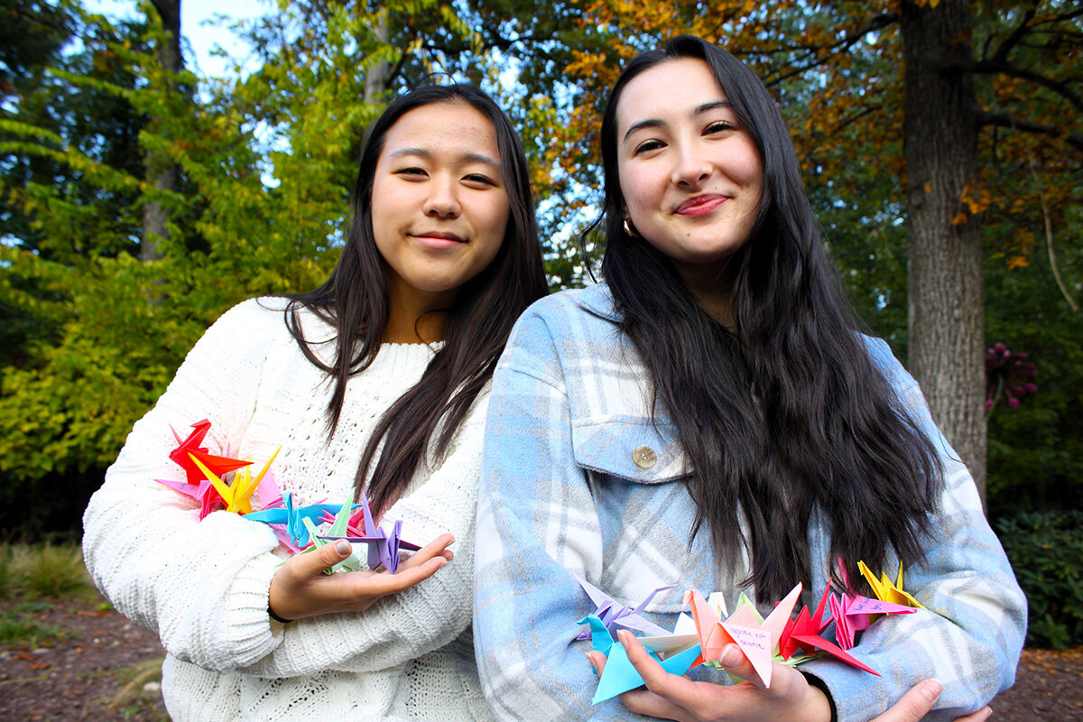 Severna Park High School juniors Hannah Kim, left, and Kateri Jarvis tossed some of the origami cranes created by members of their school’s chapter of the Wishing Crane Project into the air. They were pictured in the Michael Stanley Children’s Garden on the John & Cathy Belcher Campus of Hospice of the Chesapeake in Pasadena.