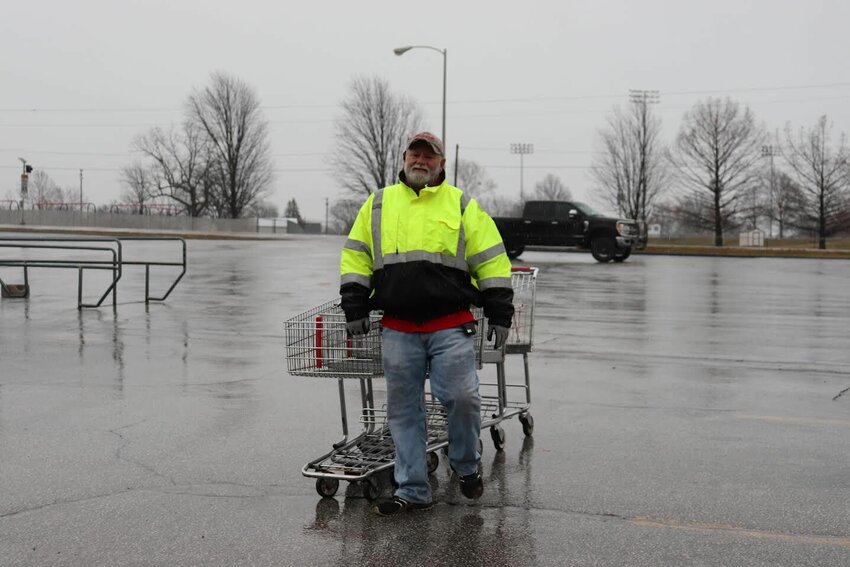 Terry Rager enduring the cold, rainy weather with a smile on his face as he brings the carts in from the parking lot at Wood's grocery store in Stockton.