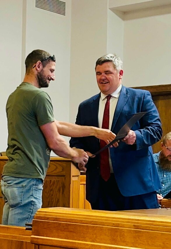 Jonathan Bilyeu is presented with a his Certificate of Graduation by Judge Dawson.