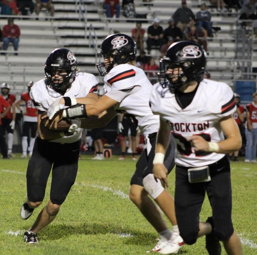 Easton Hubbard hands the football off to Jack Rickman as Logan Reser leads the way last Friday against Ash Grove. The Tigers picked up the win, 18-0.